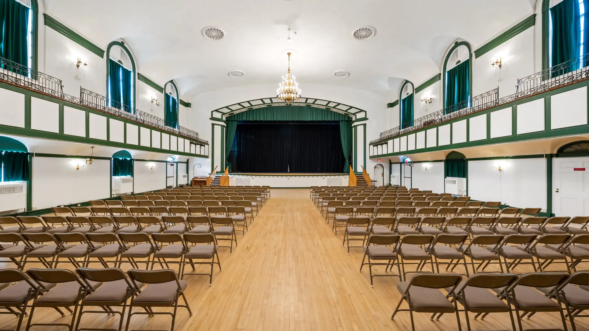 The auditorium with balconies and raised, curtained stage at the Harrietstown Town Hall.