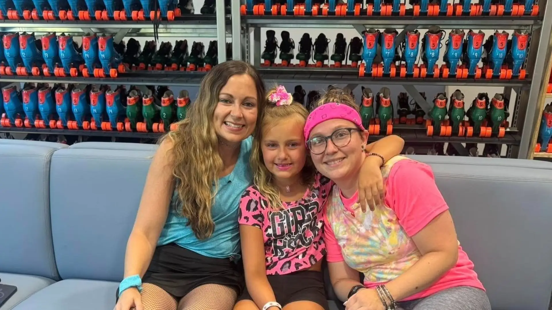 Skaters on a bench with a wall of shelves with skates behind them.