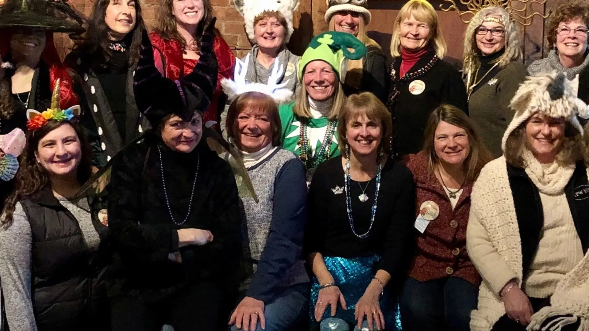 A group of smiling women wearing silly hats and carnival beads