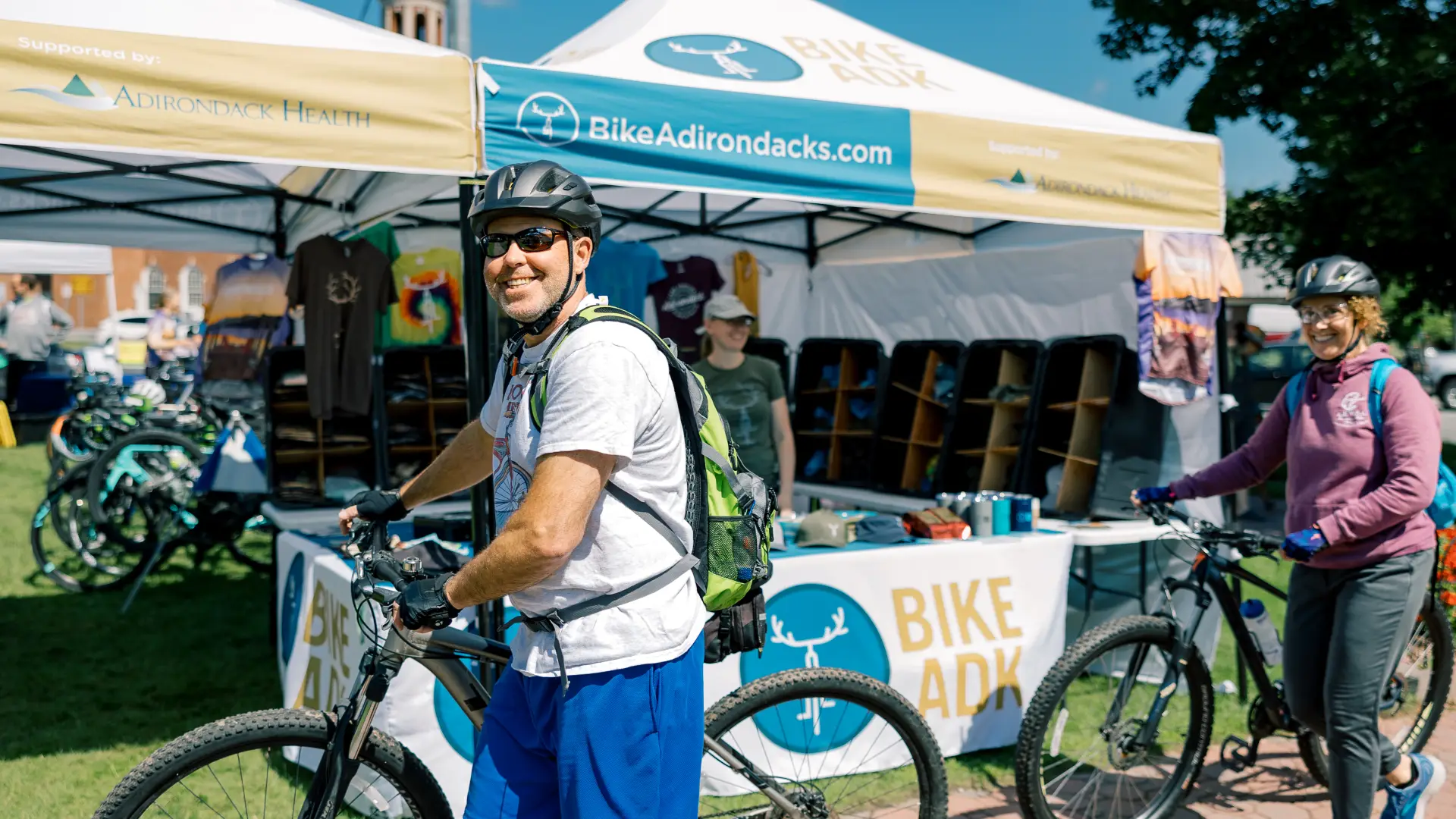 smiling man on bike with vendor tent in the background 