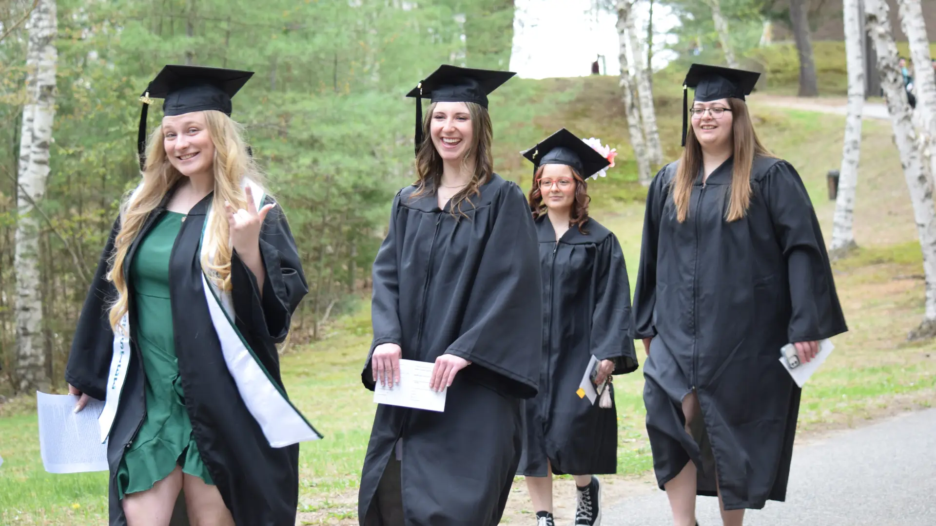 Smiling graduates walk by.