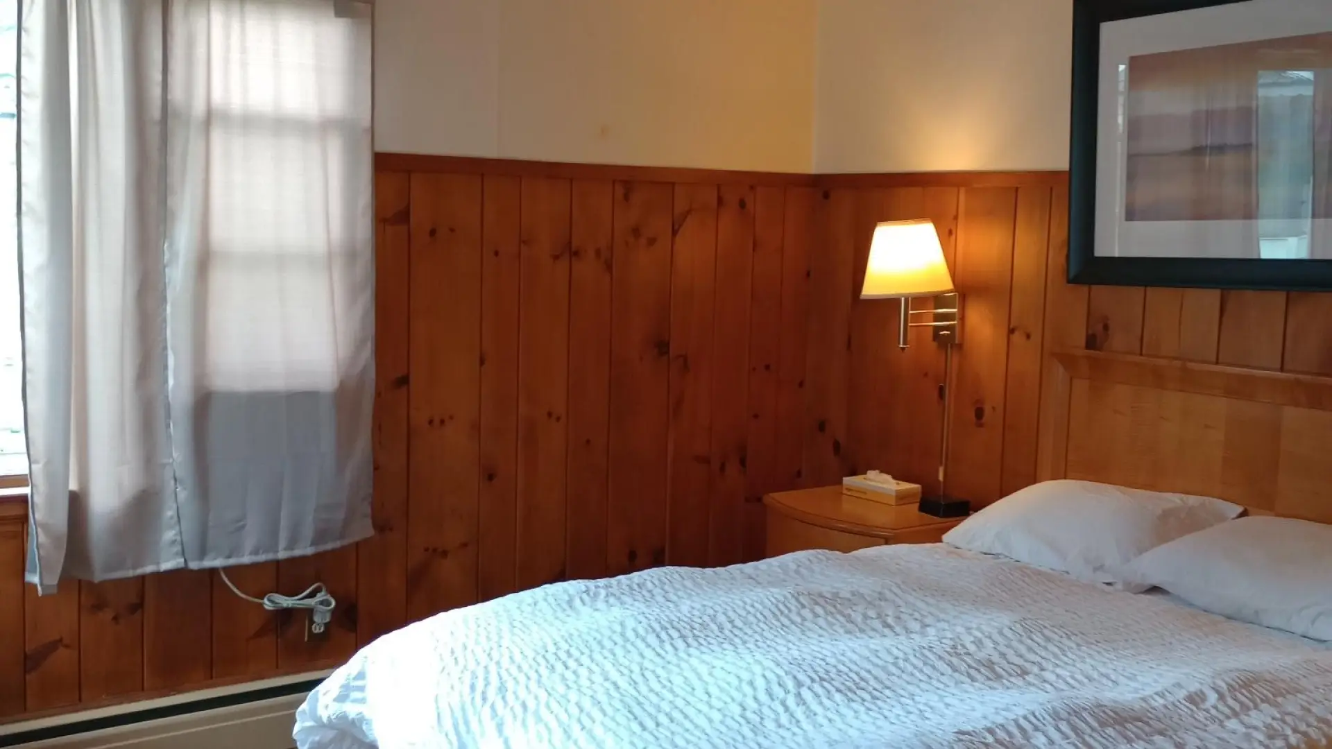Plush white linens on a queen bed in a wood paneled room at The Ashley.