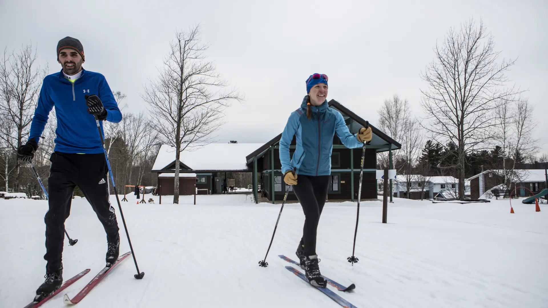 Couple skiing at view of the Dewey Mountain Lodge in the background.