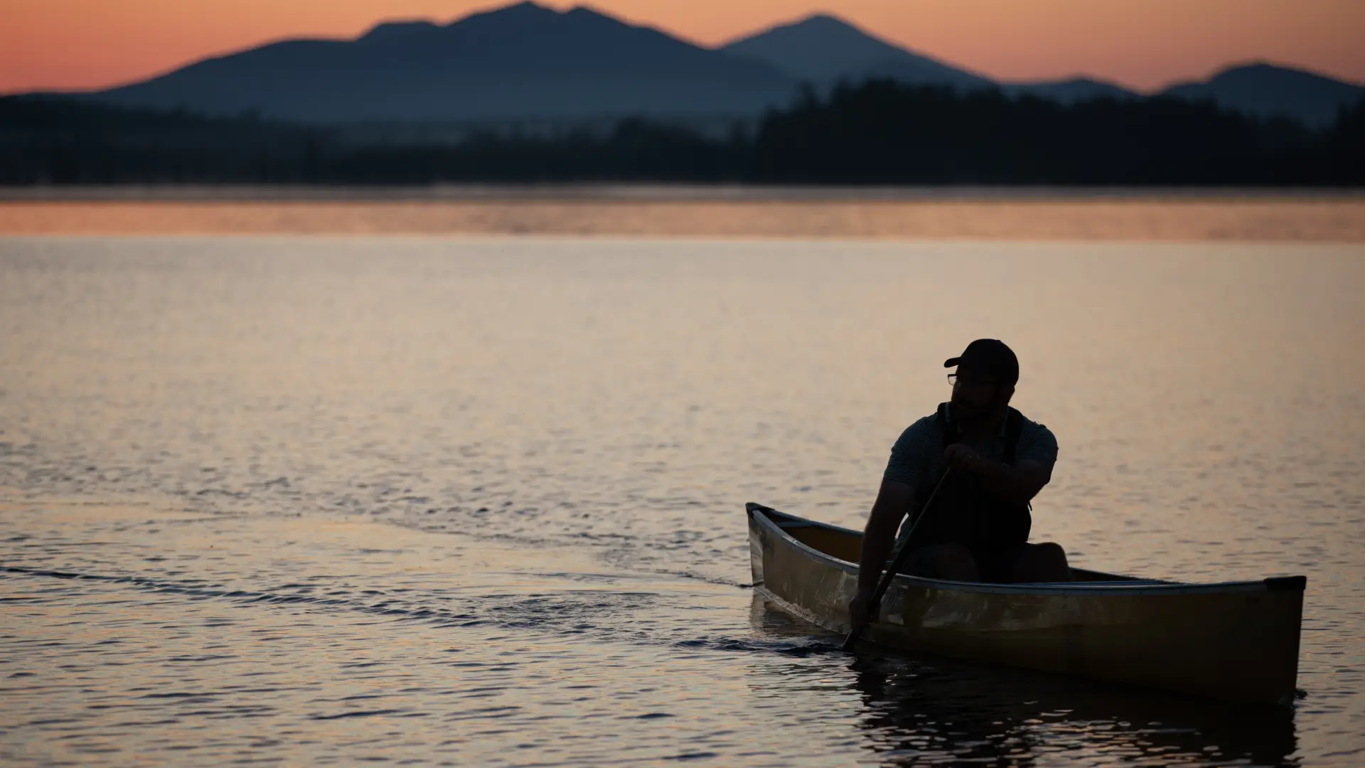 A solo paddler at sunset with the mountains in the back