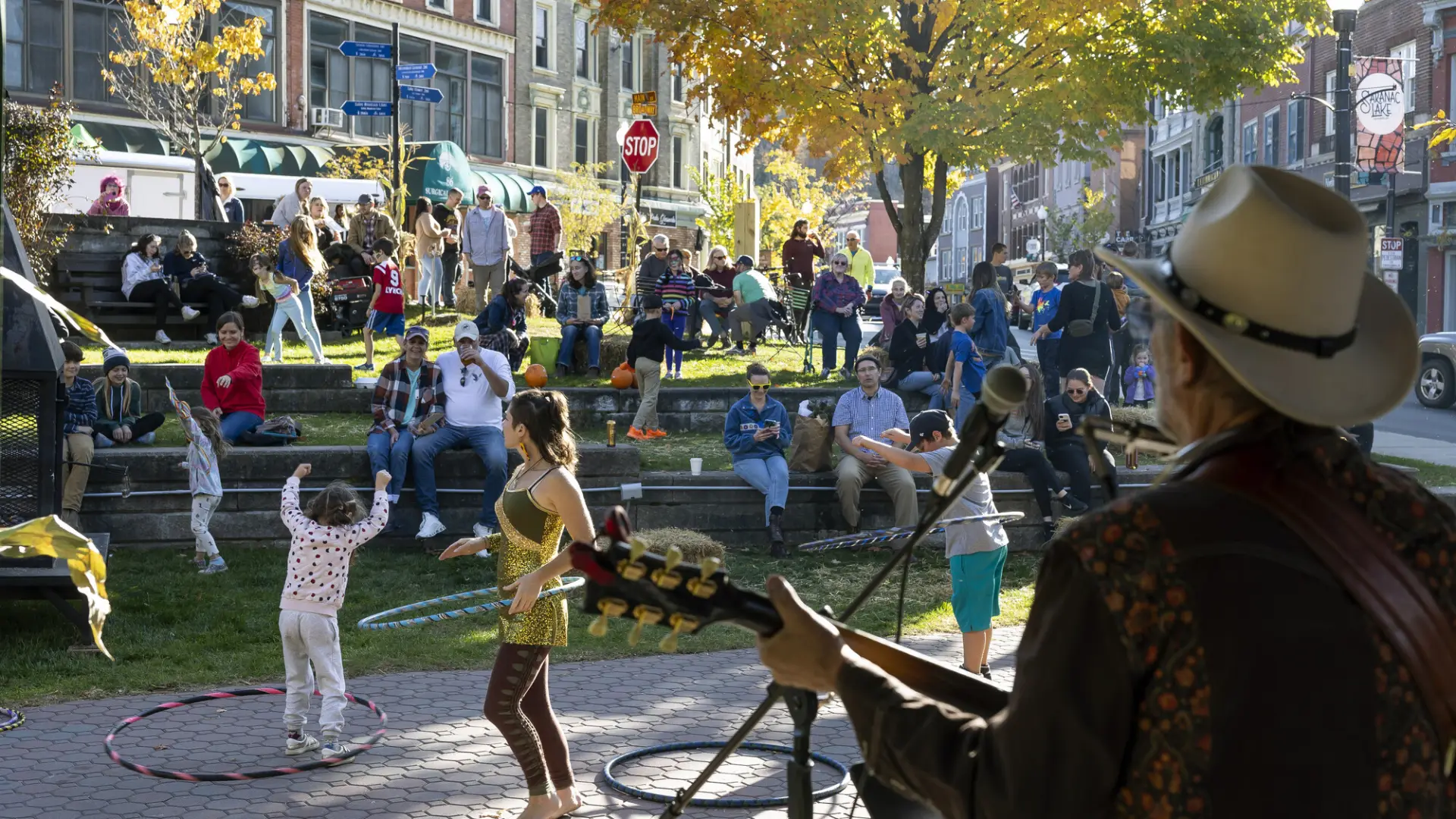 A man plays guitar for a crowd of people dancing in a park. 