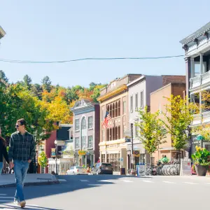 A man and woman cross the street in the downtown of a small town in fall.