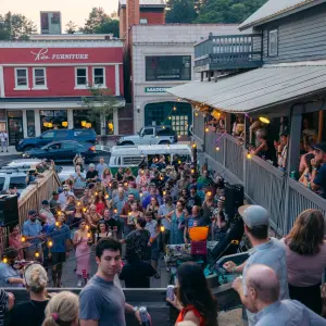 A crowd of people dance at an outdoor music venue in the middle of a small town. 
