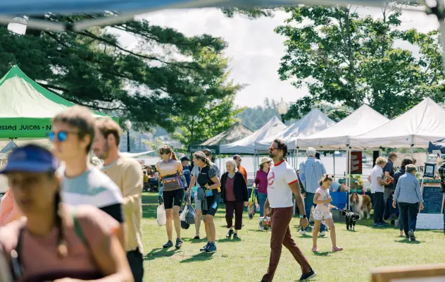 A group of people walk around a farmers market.