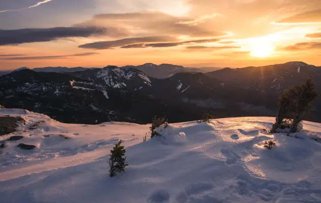 A snowy mountain summit at sunset.