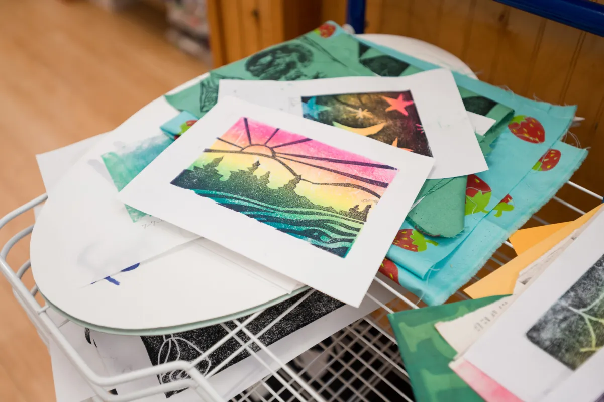 Handmade woodcut prints piled on a table.