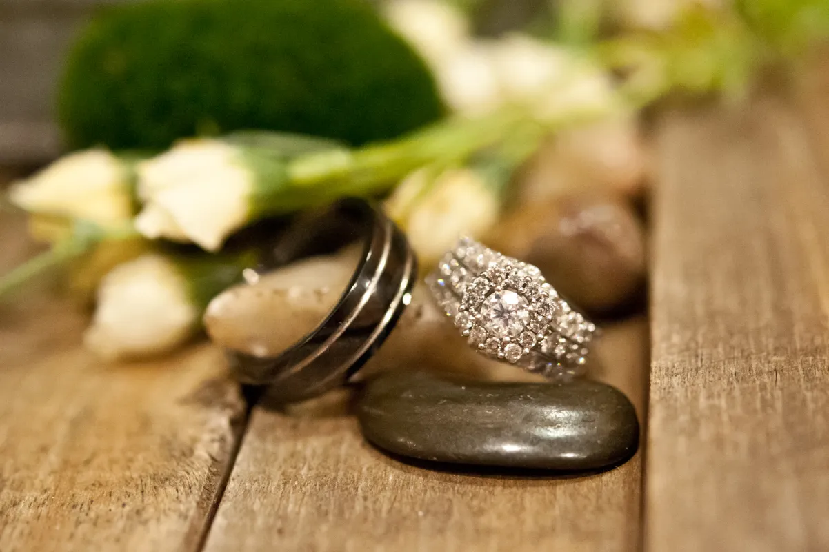 Two rings sit on top of each other with flowers in the background.
