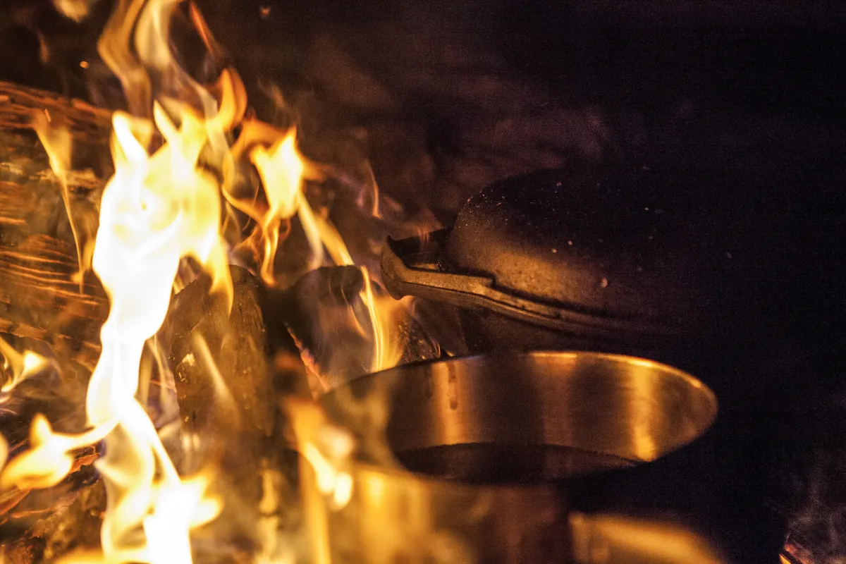 A cast iron skillet sits in a fire.