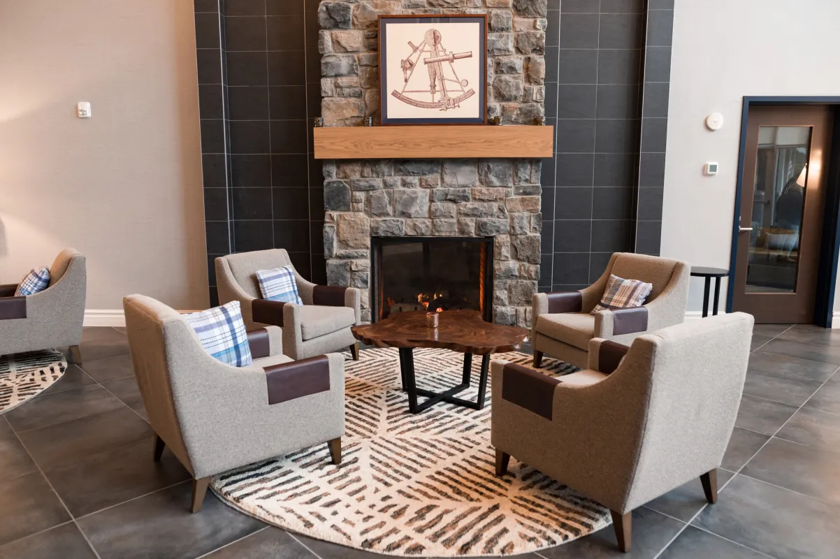A lounge area in an upscale hotel features a stone fireplace and cozy chairs.