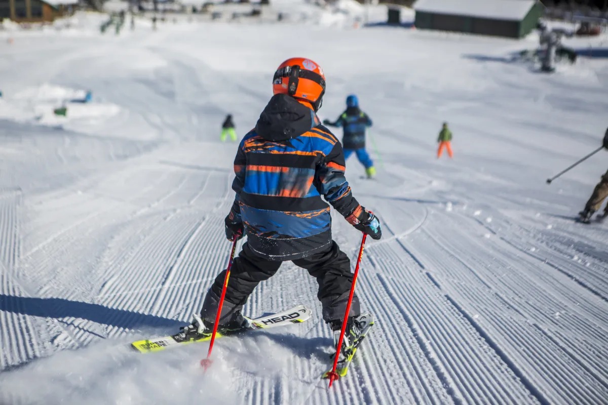 A child skis down a mountain in winter.