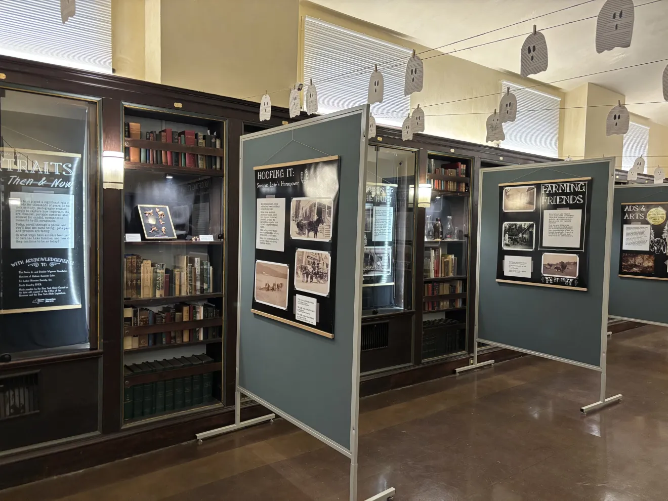A museum exhibit room featuring glass cases and festive Halloween decor.