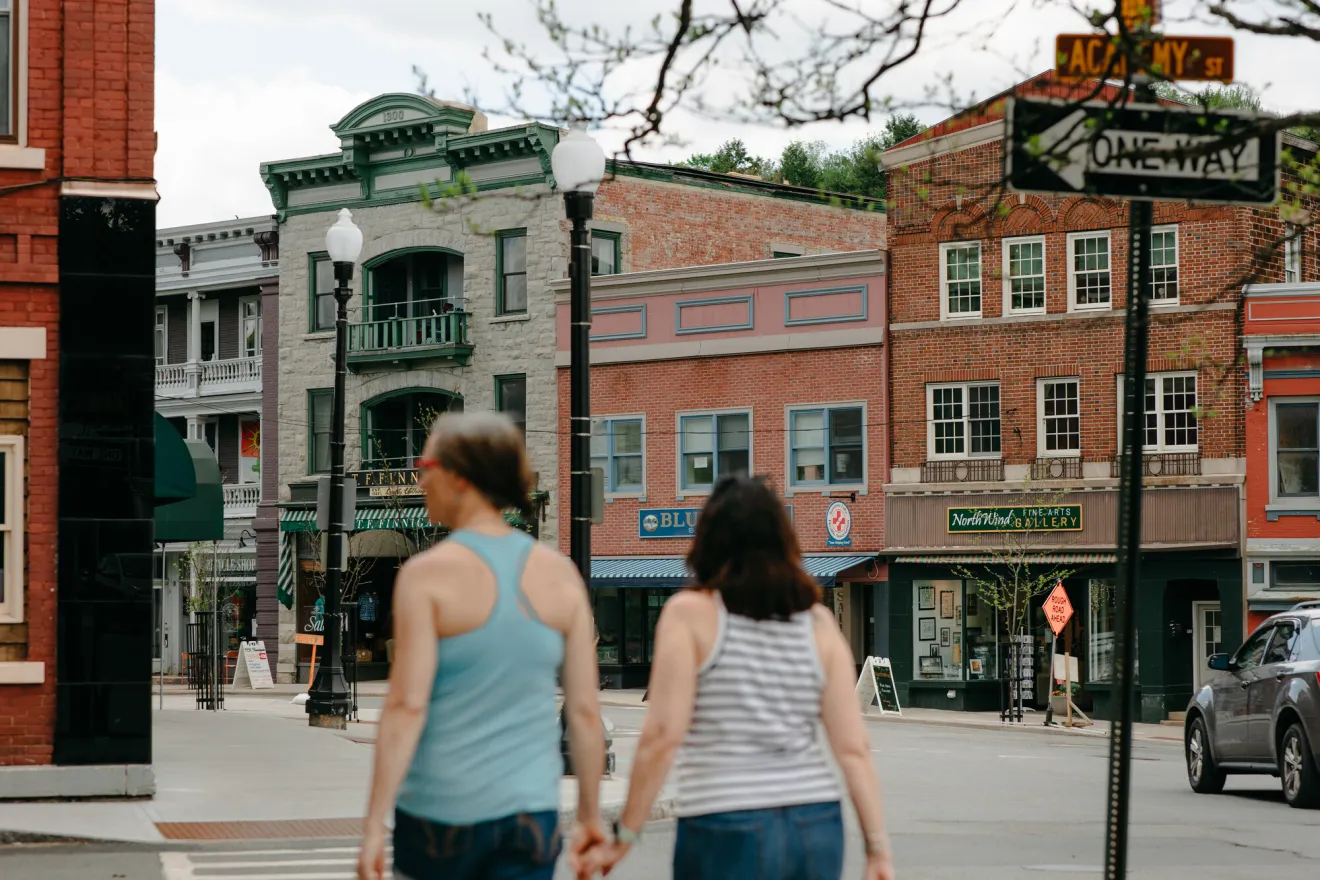 Two women walk on the main street of a small town. 