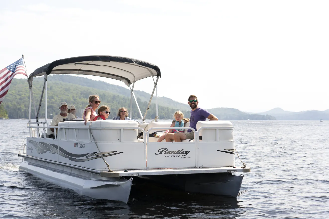 A family rides a pontoon boat on a lake. 