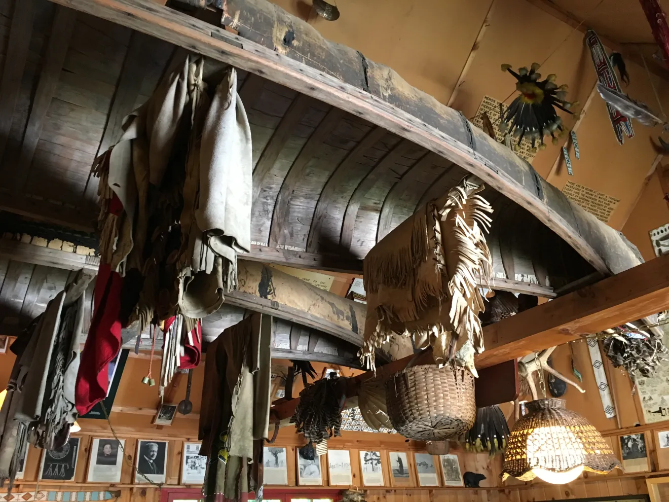 Mohawk artifacts hang from an upsidedown birchbark canoe in an indigenous museum.