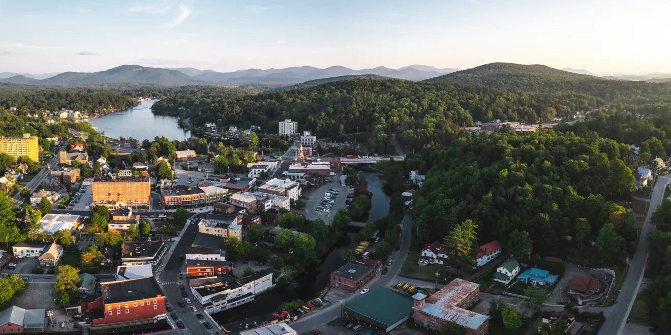 An aerial view of a small town in the mountains with a lake in the background. 