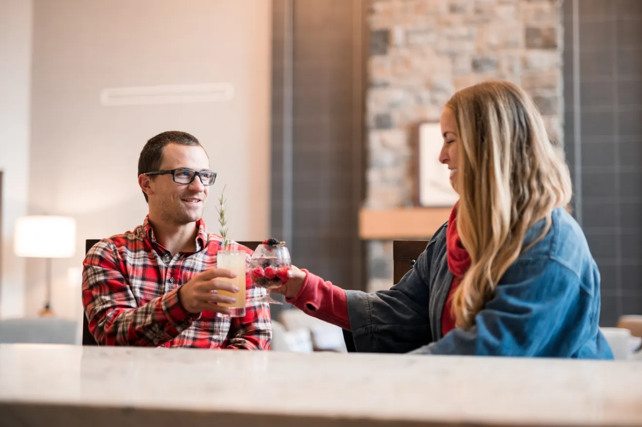 a man and woman cheers drinks at a hotel bar.