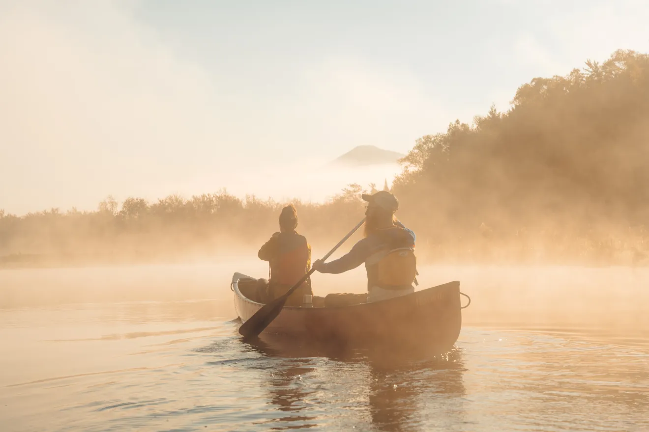 Two people paddling a canoe in Saranac Lake.