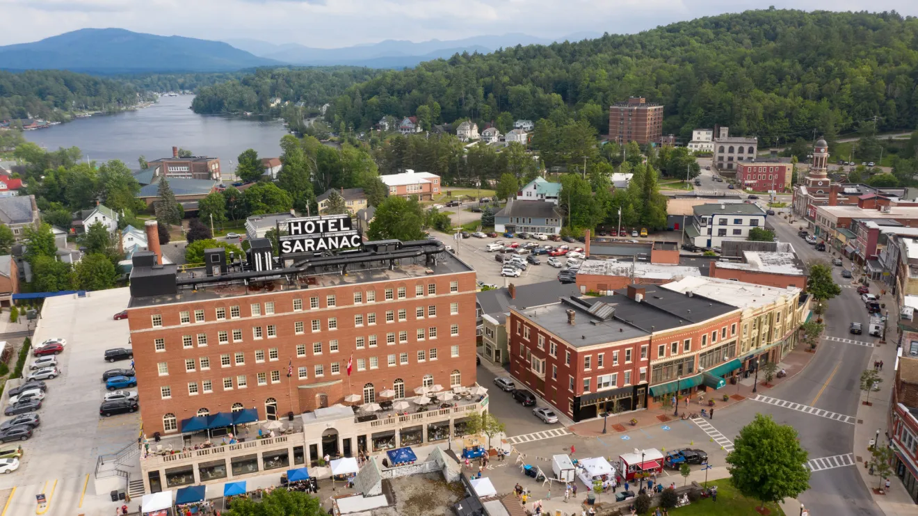 An aerial view of a hotel in a small town with a lake in the background. 