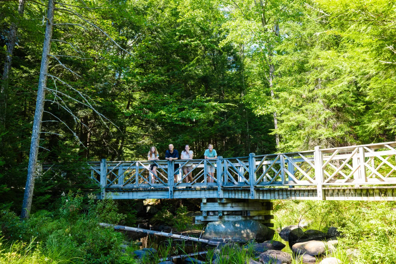 A family stands for a picture on a bridge. 