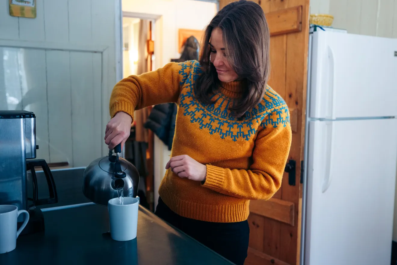 A woman pours coffee in a kitchen.