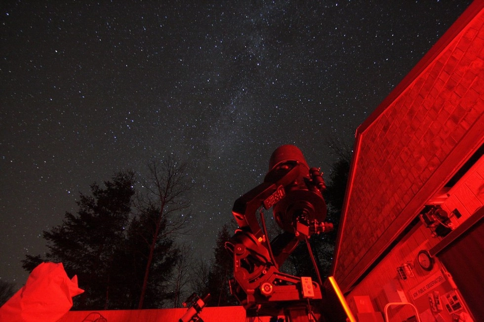 A telescope looks up at the stars, glowing with red light