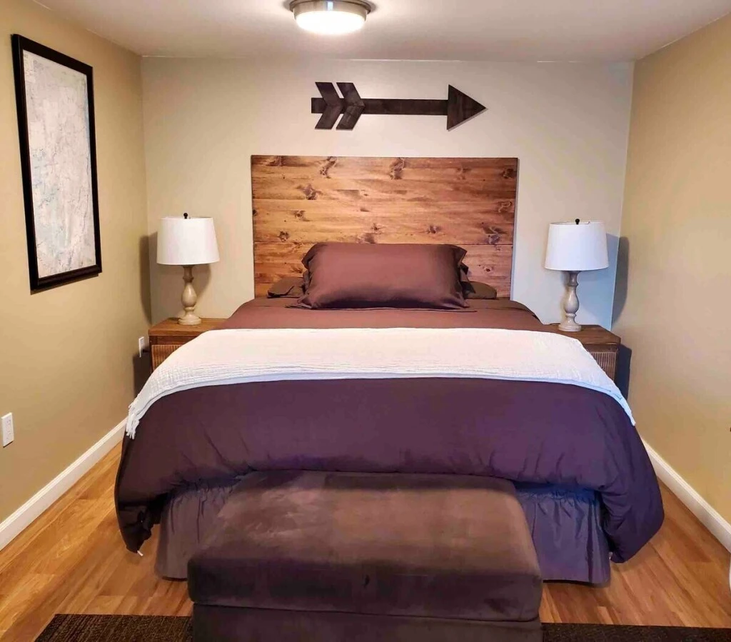 The primary bedroom with a large bed, wooden headboard and a wooden arrow decor on the wall.