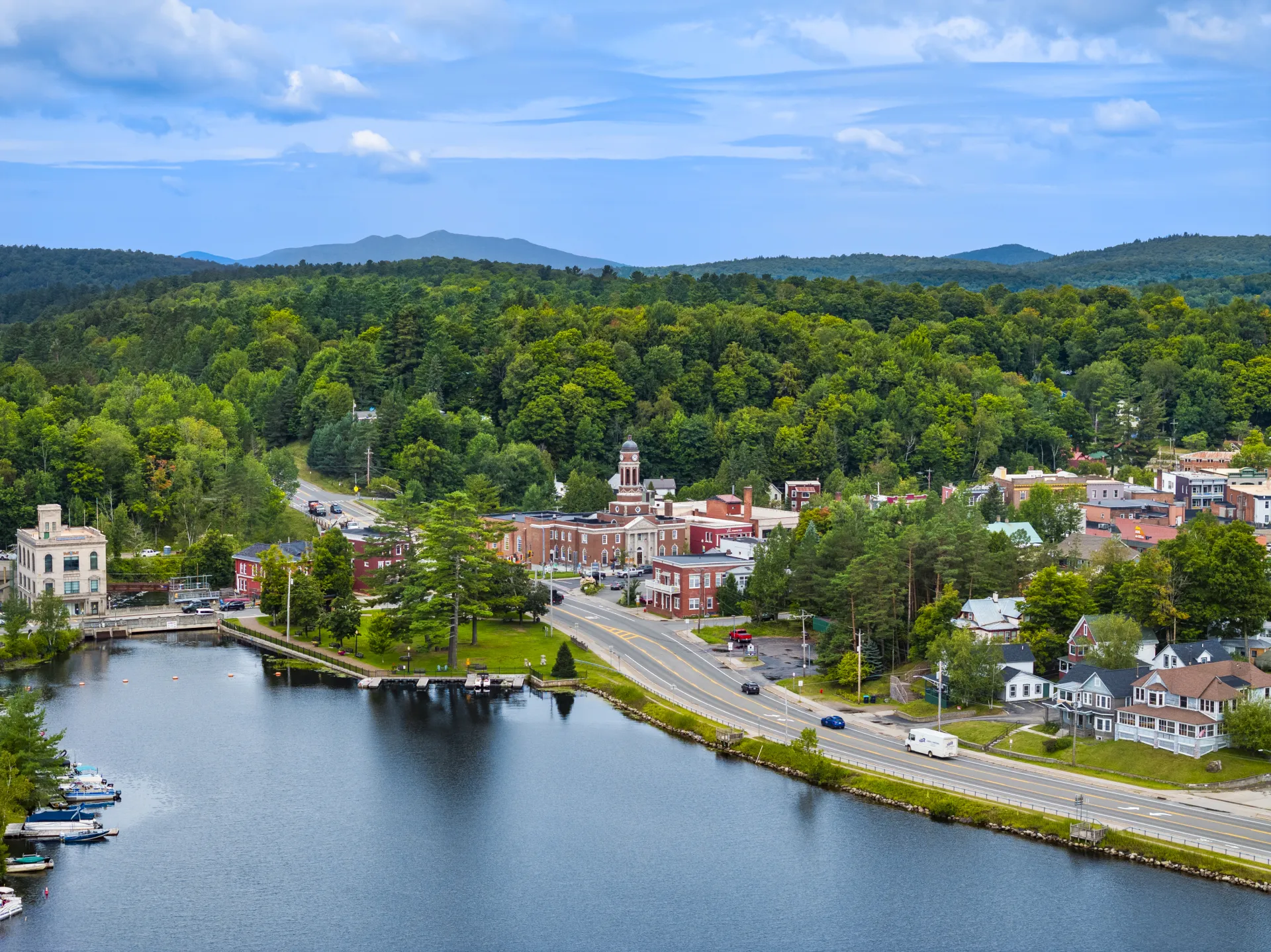 A backed up aerial view of the clock tower at the Harrietstown Town Hall and proximity to Lake Flower