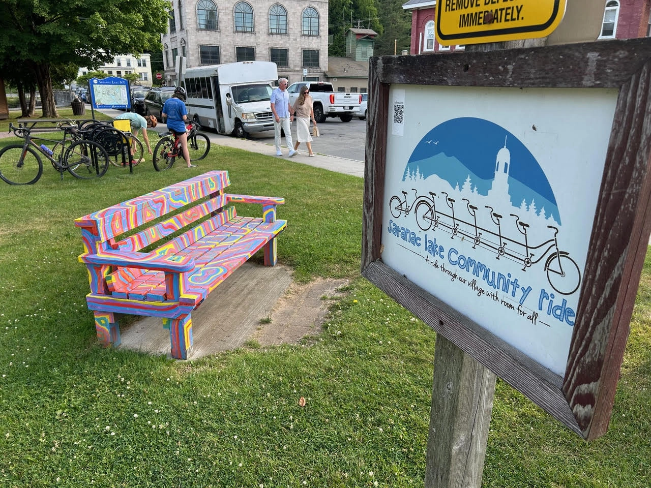 colorfully painted bench beside a community bike ride sign 