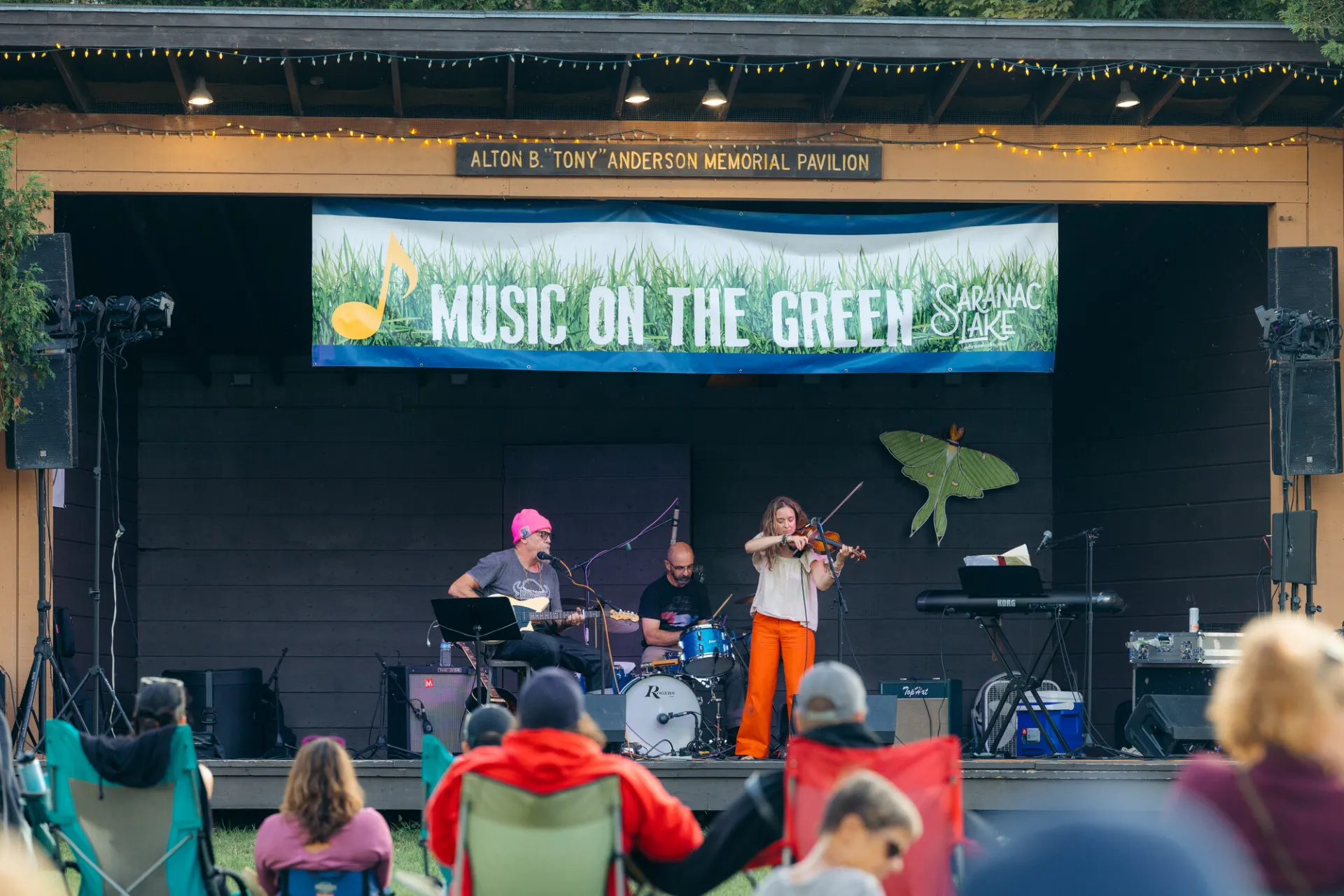 A band plays music for an audience in a park. 