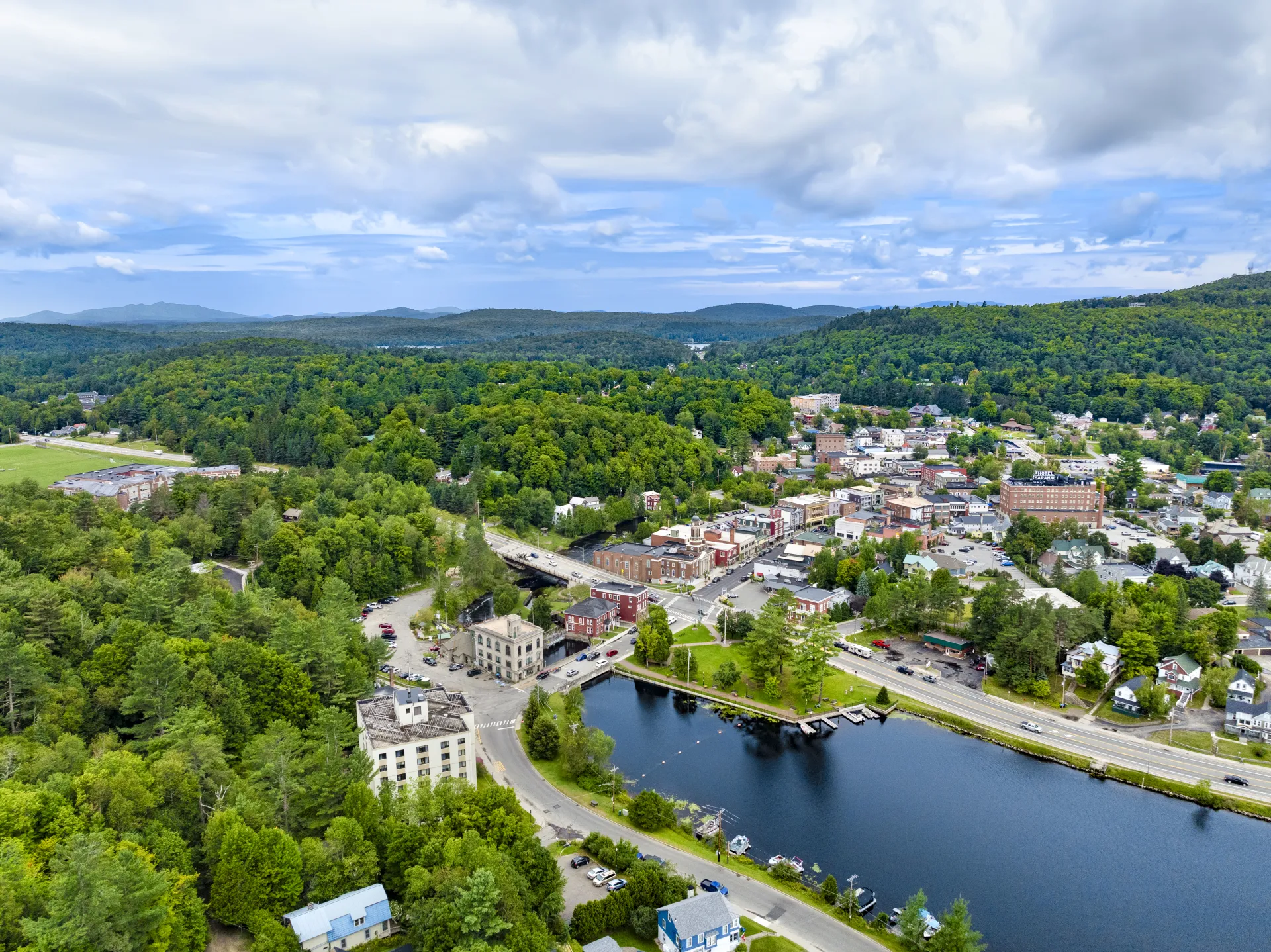 A backed up aerial view of the clock tower at the Harrietstown Town Hall and proximity to Lake Flower