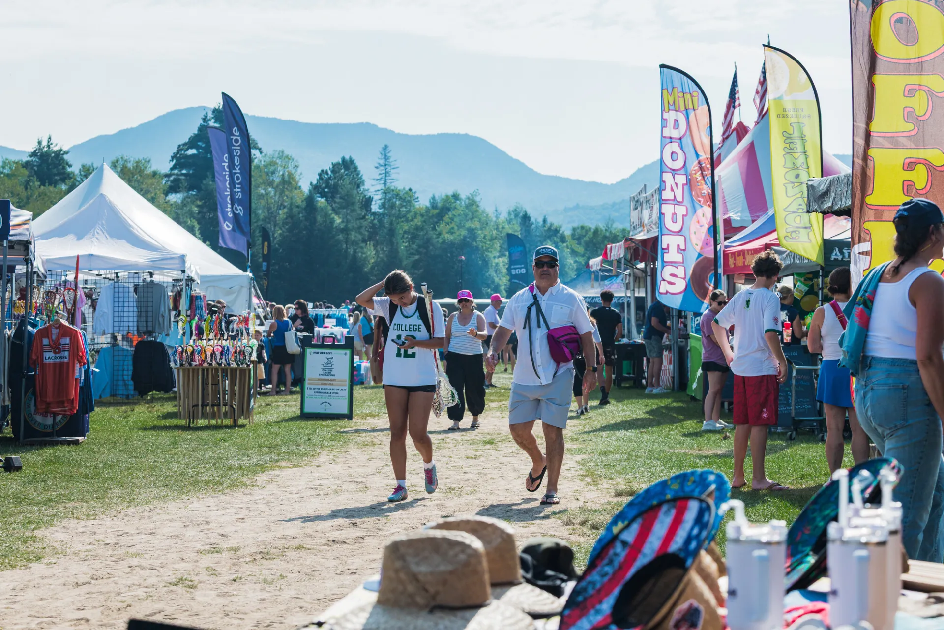 People walk down roadway flanked by vendors at Lacrosse tournament in Lake Placid