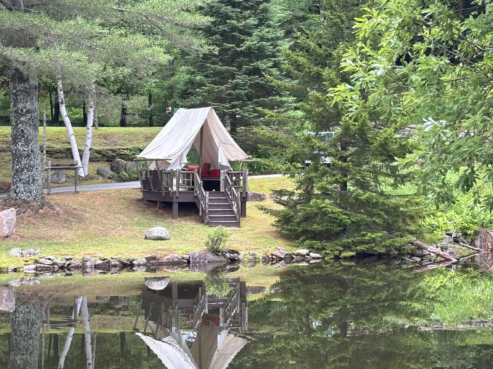 A fabric tent covering a raised deck next to the pond