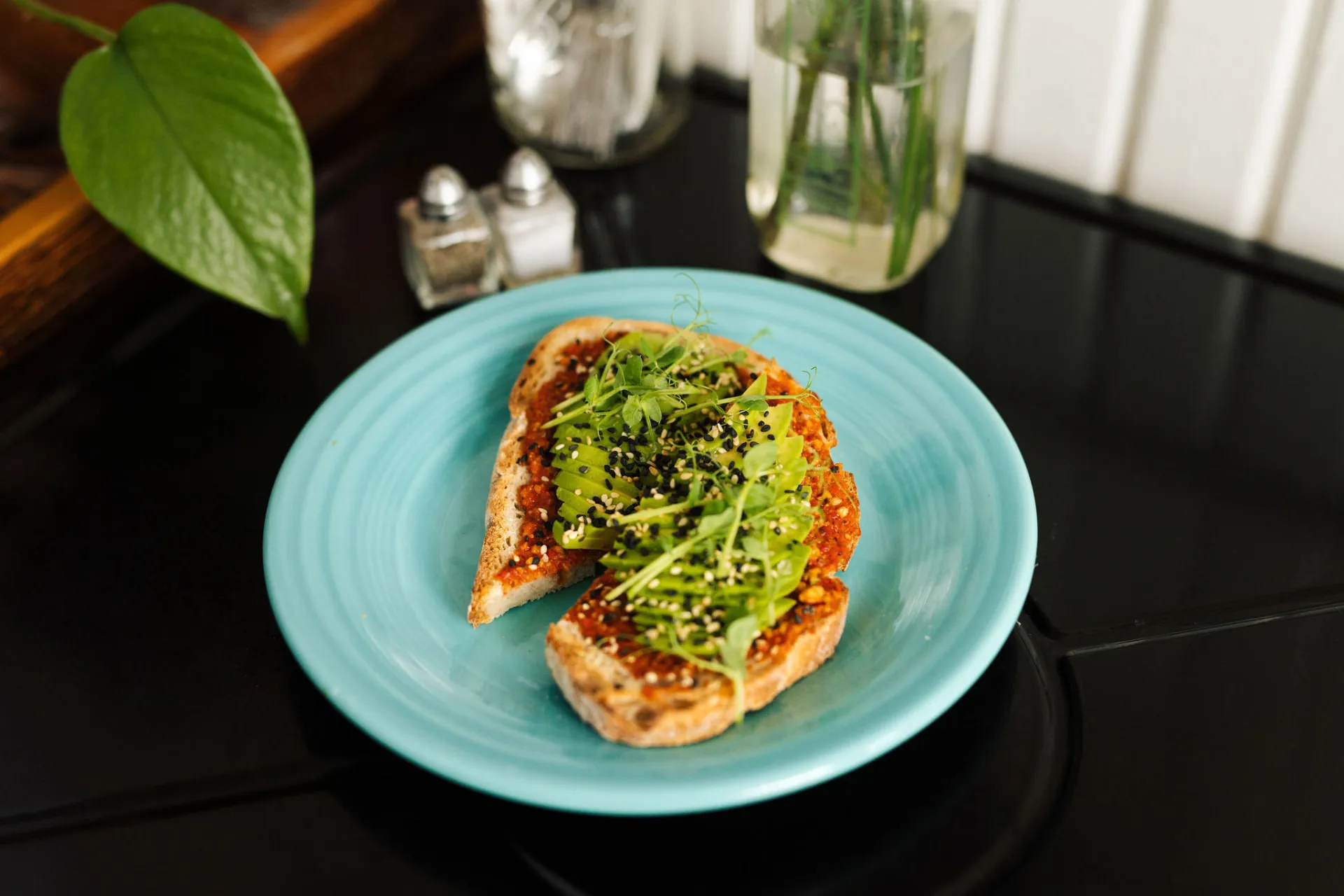 Avocado toast with sprouts on a colorful plate.