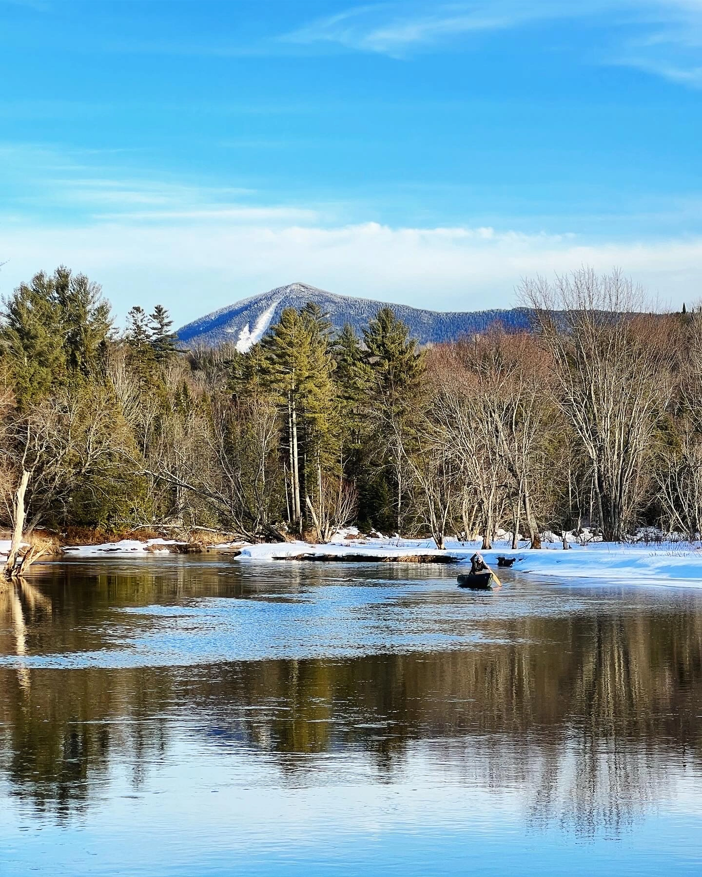 A view of a snow covered slide on a mountain from the water.