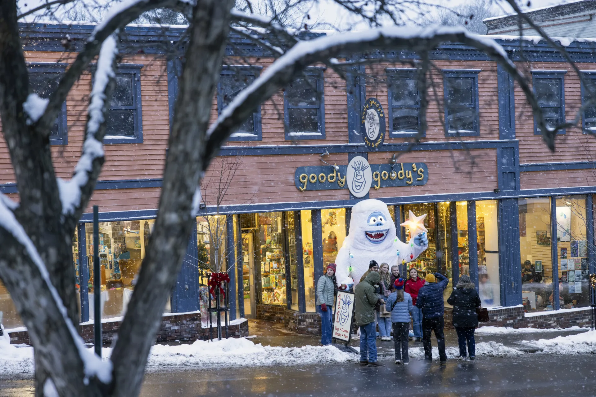 A family poses in front of a winter yeti on a main street. 
