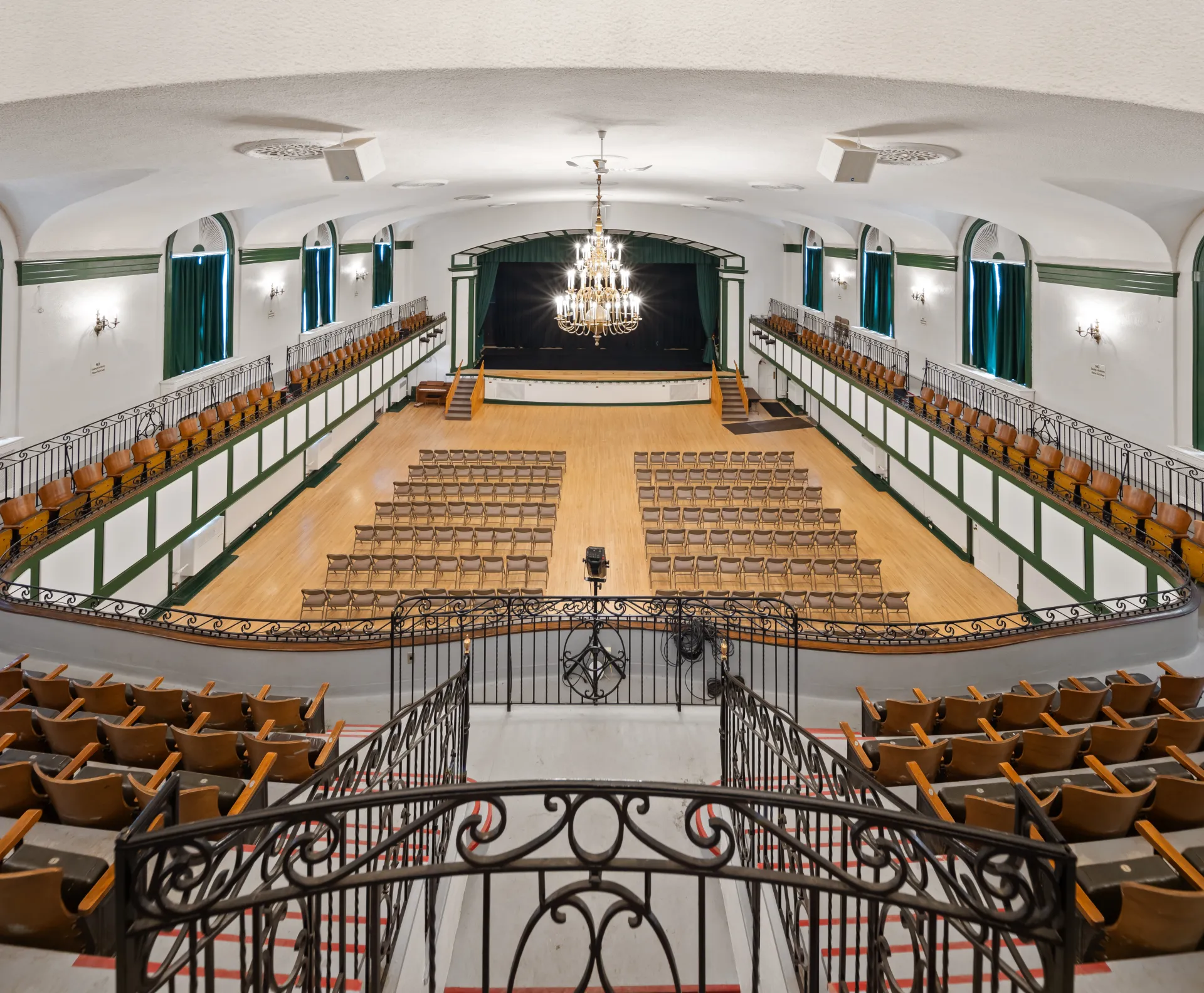 The auditorium with balconies and raised, curtained stage at the Harrietstown Town Hall, viewed from the balcony