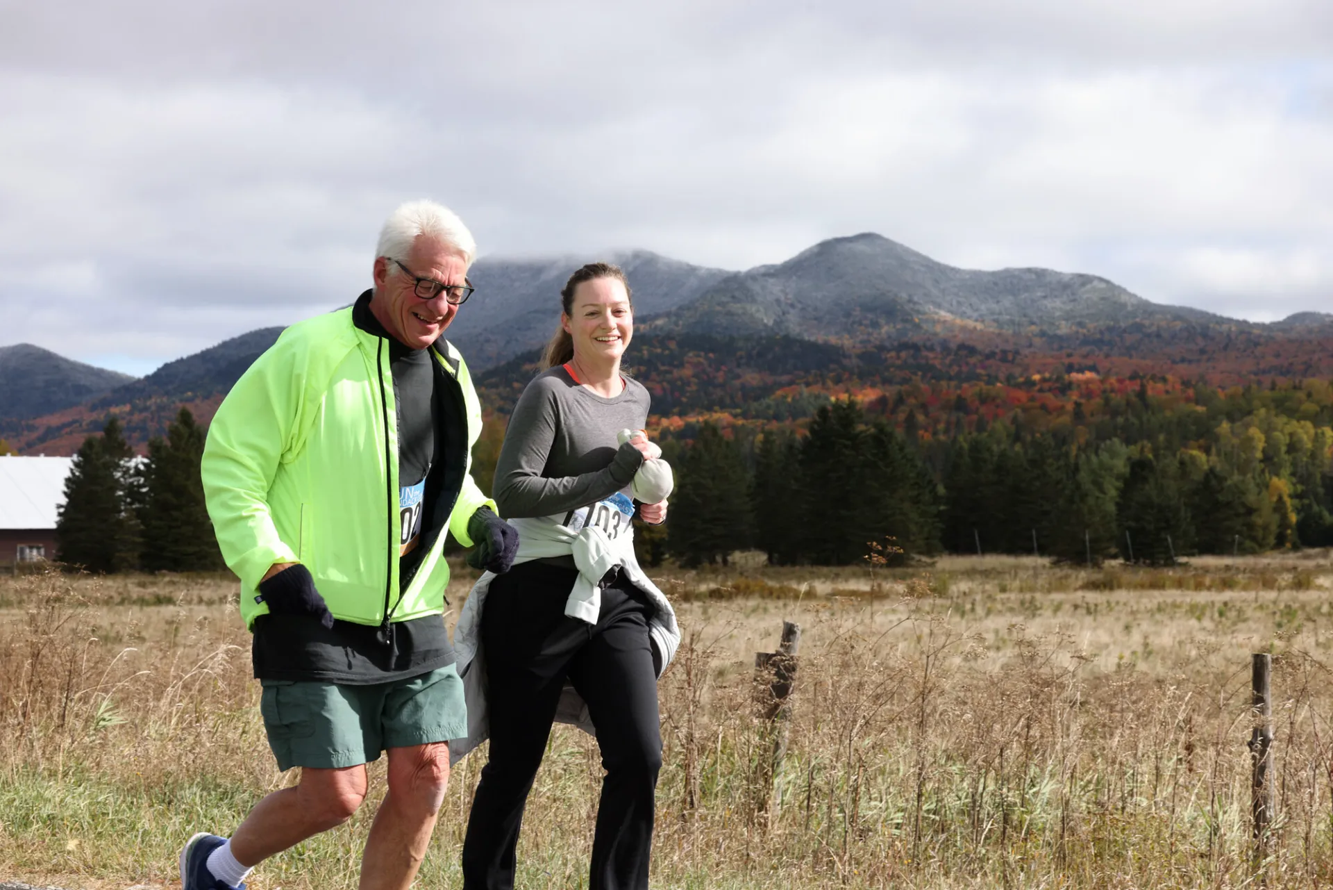 Man and woman running side by side on road with mountain in background