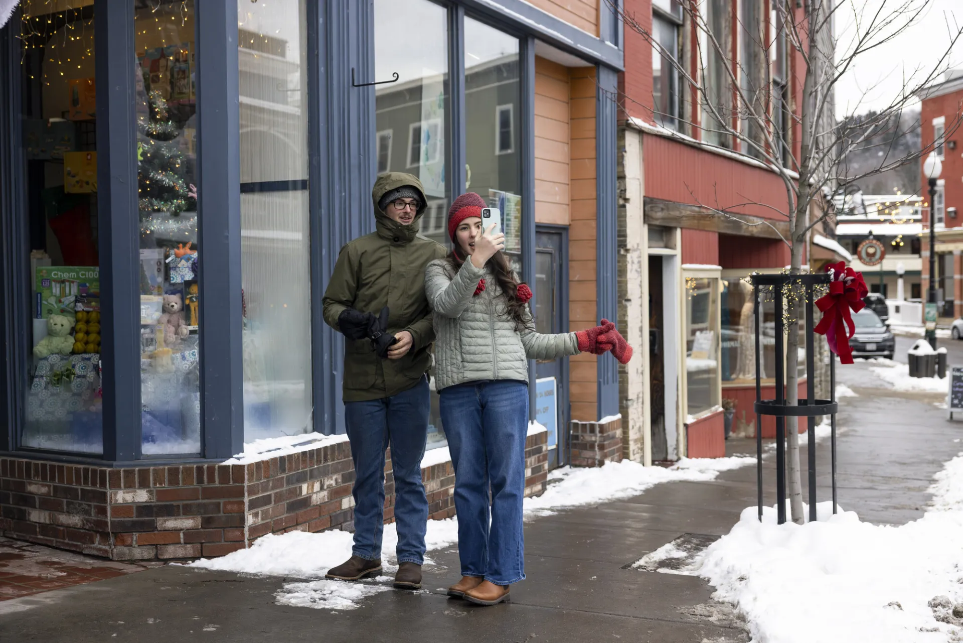 A couple taking photos of winter in downtown Saranac Lake.