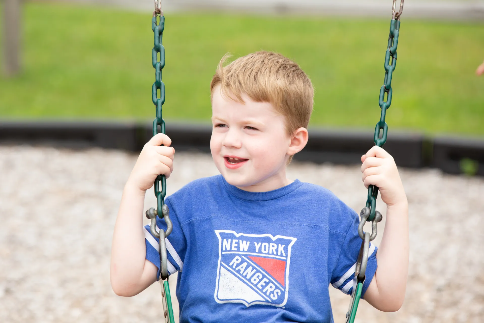 A young kid plays on a swingset