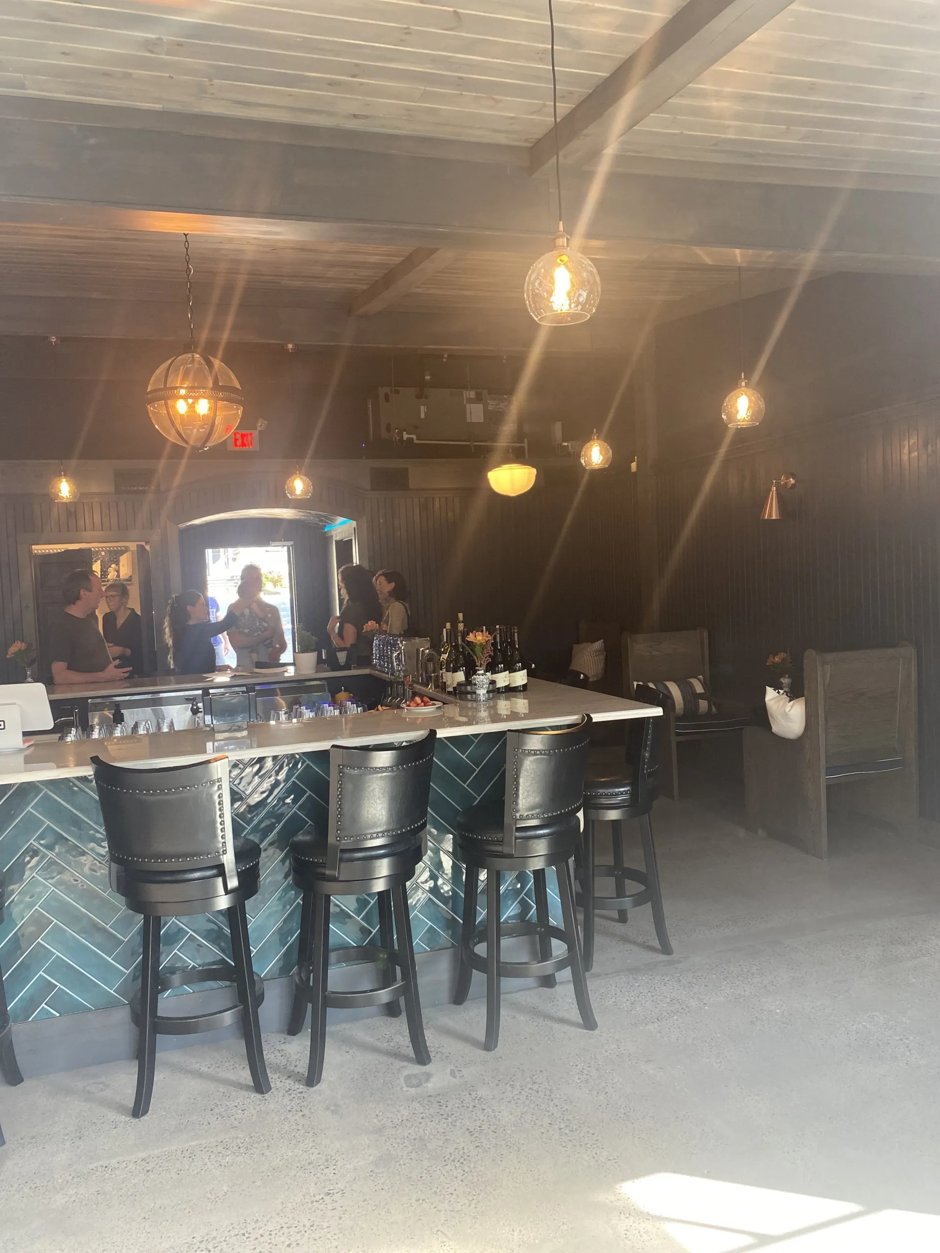 Looking into the bar area at the herringbone patterned deep green tiles on the bar