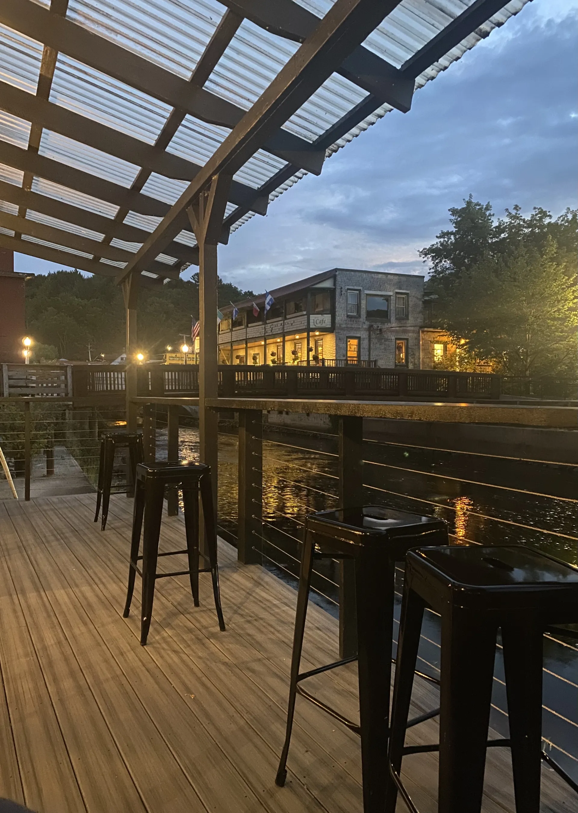 The covered terrace by the river illuminated at dusk