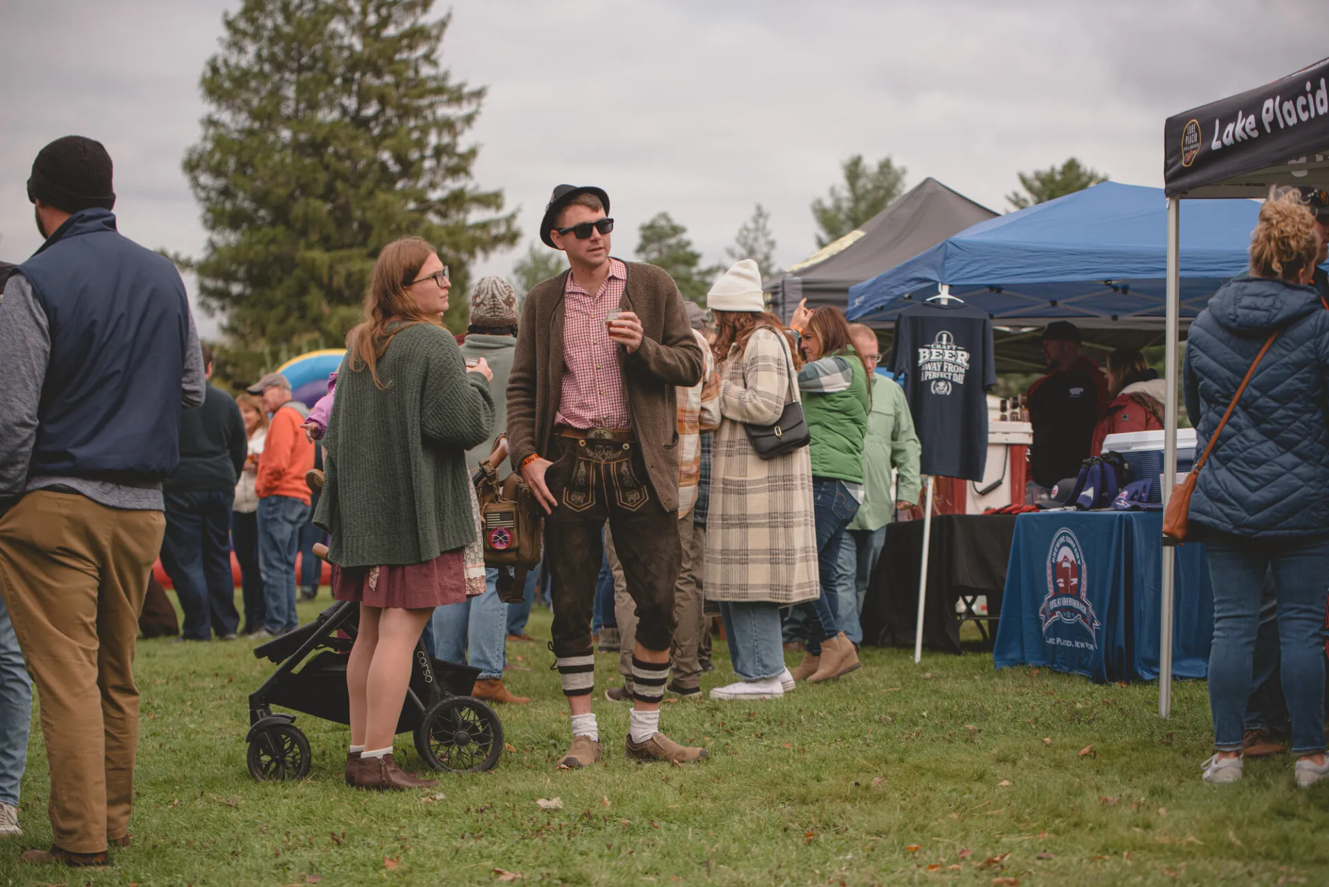 a man in german traditional clothes enjoys a fall market. 