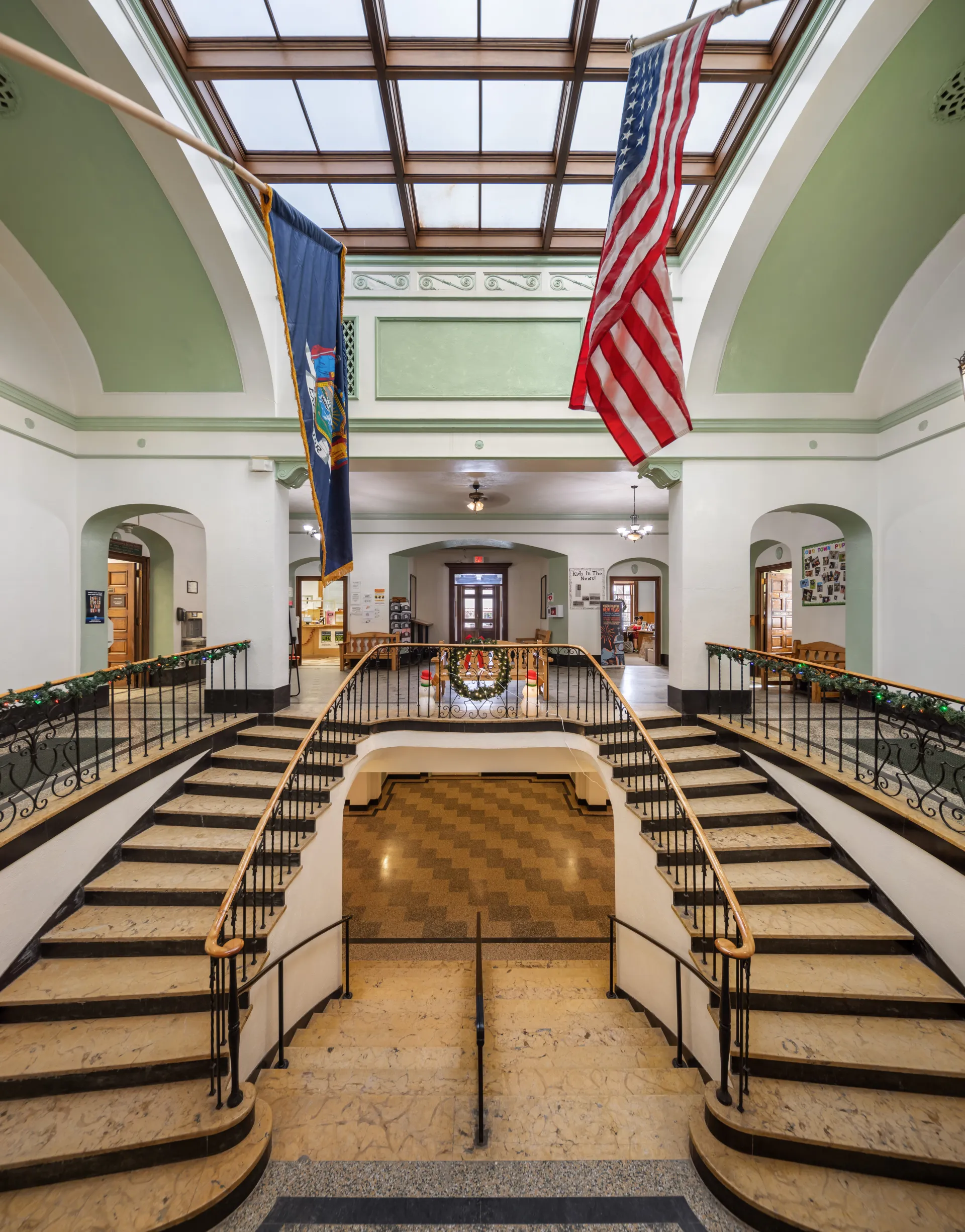 A grand, double sided staircase with stone steps and sky lights at the Harrietstown Town Hall.