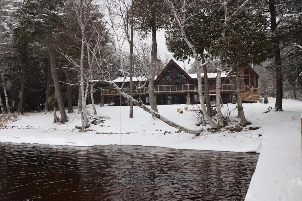 A winter scene at Alpenglow Lakeside Lodge showing the large lawn blanketed in snow.