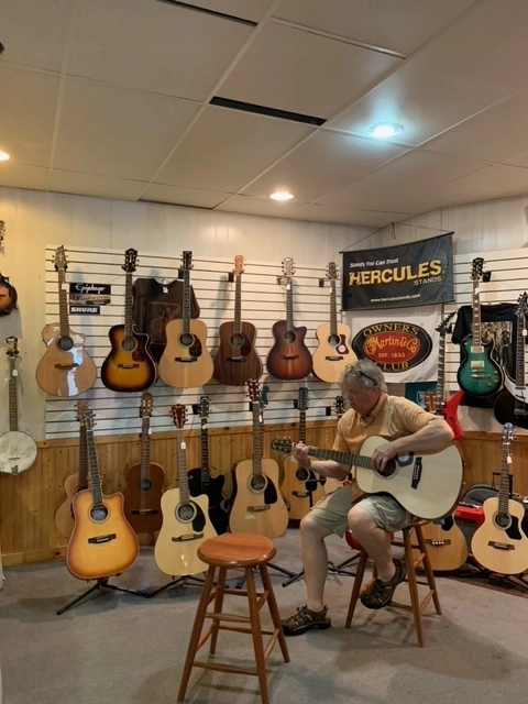 A man plays guitar at a guitar shop. 