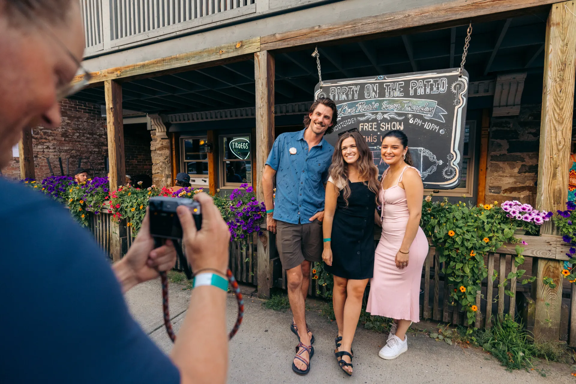 A group of friends smile and pose for a picture in front of a restaurant. 